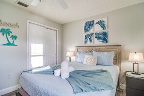 Ein Schlafzimmer mit Bett, Nachttisch, Lampe und Wandbildern.