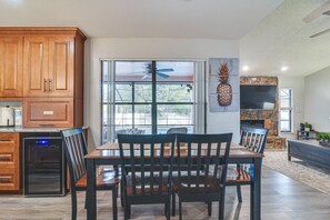 A kitchen with wooden cabinets, a dining table with chairs, and a sliding glass door leading to a patio area. - Largo Oasis w/ Pool & Grill~6 Mi to Beach! (Largo)