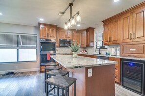 A modern kitchen with wooden cabinets, a central island, and built-in appliances. - Largo Oasis w/ Pool & Grill~6 Mi to Beach! (Largo)