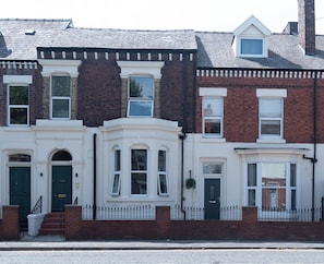 En rad av radhus med vita fasader, detaljer i tegel och många fönster.