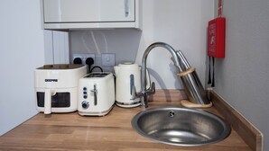 Eine Küchenzeile mit einer GEEPAS-Mikrowelle, einem Breville-Toaster, einem Breville-Wasserkocher und einer Spüle aus Edelstahl.