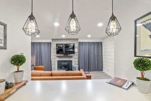 A modern living room with a sofa, a fireplace, and pendant lighting. - 1BR Condo for 4 w/Hot Tub, Near Shuttle & Shopping (Mammoth Lakes)
