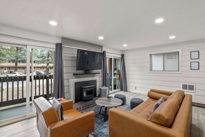 A modern living room with a fireplace, leather sofa, and a television. - 1BR Condo for 4 w/Hot Tub, Near Shuttle & Shopping (Mammoth Lakes)