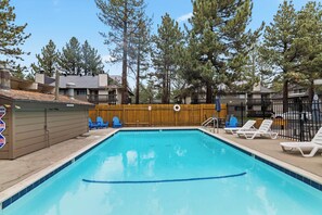 A swimming pool with lounge chairs and a wooden fence. - 1BR Condo for 4 w/Hot Tub, Near Shuttle & Shopping (Mammoth Lakes)