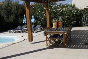 A poolside area with lounge chairs, a table, and potted plants. - Holiday Home 'Le Rêve D'enfant' with Private Pool, WiFi, and Air Conditioning (Narbonne)