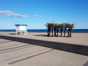 Une plage avec un poste de surveillance pour les sauveteurs, des palmiers et un ciel dégagé.