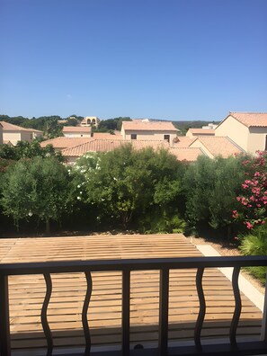 Un quartier résidentiel avec des maisons aux toits de tuiles rouges, une végétation luxuriante et une terrasse en bois.