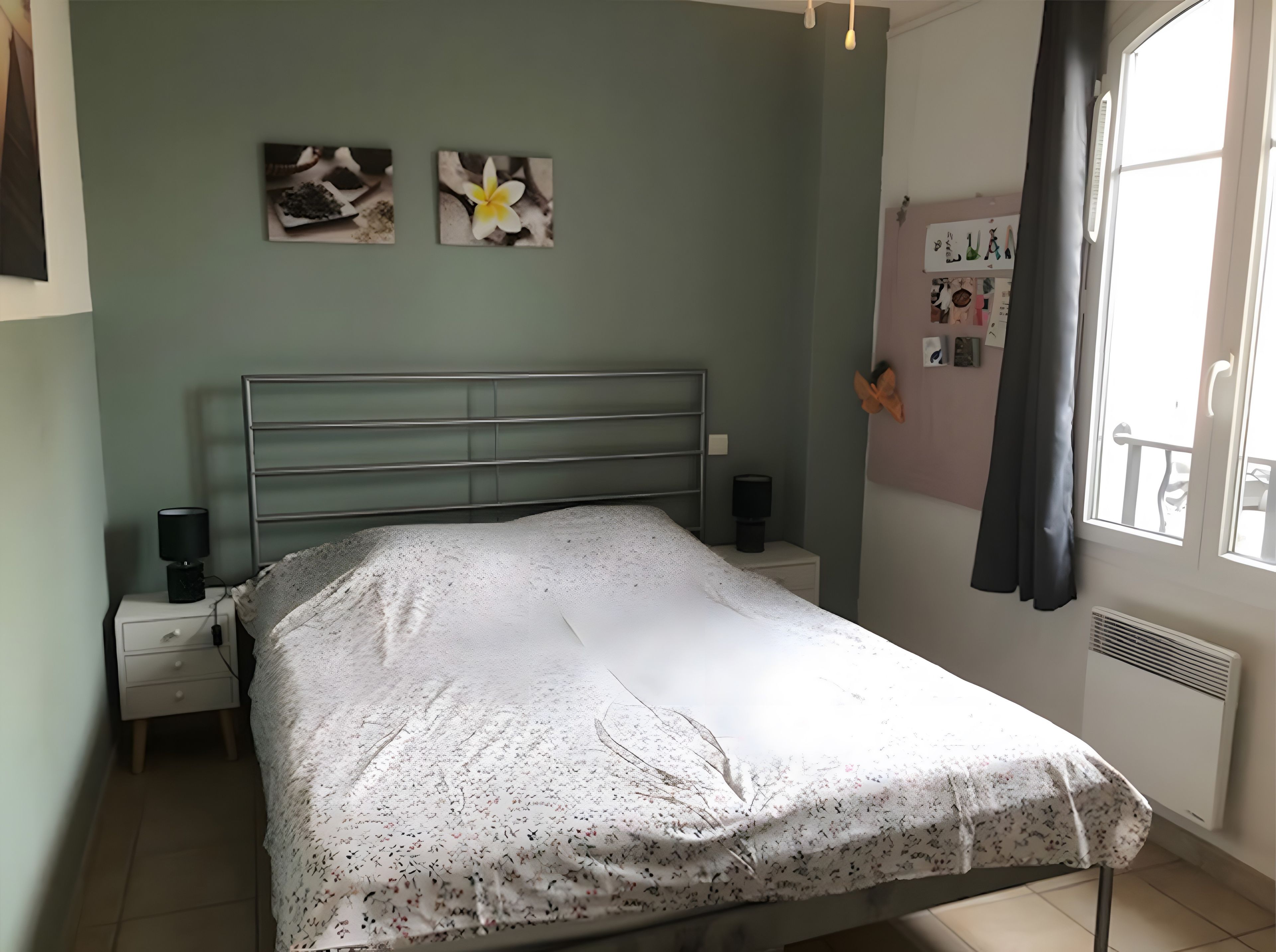 Une chambre à coucher avec un lit, des tables de chevet, une étagère fixée au mur et une fenêtre avec des rideaux.