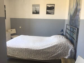 A bedroom with a bed, a nightstand, a desk, and two framed pictures on the wall. - Holiday Home 'Le Rêve D'enfant' with Private Pool, WiFi, and Air Conditioning (Narbonne)
