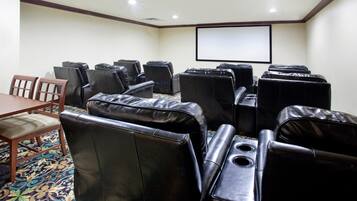 A conference room with black leather chairs, a wooden table, and a large screen.