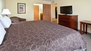 Une chambre d’hôtel avec un grand lit, une télévision, une commode et une porte donnant sur un couloir.