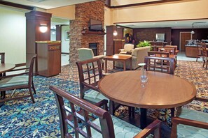 Un hall de hotel con chimenea central, zona de estar y bar.