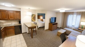 A hotel room with a kitchenette, a bed, a TV, a sofa, and a small table. - Accessible Suite | Roll-In Shower | Free Breakfast (Elkhart)