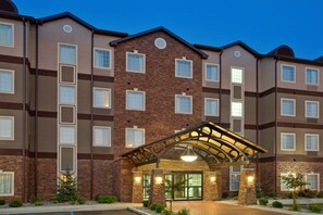 Un hotel de varios pisos con fachada de ladrillo, ventanas grandes y un área de acceso cubierta.