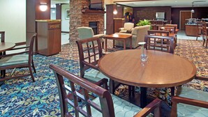 A hotel lobby with a central fireplace, seating area, and a bar. - Accessible Suite | Roll-In Shower | Free Breakfast (Elkhart)