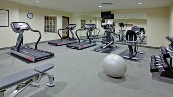 A gym with treadmills, a bench, a large exercise ball, and weight machines.