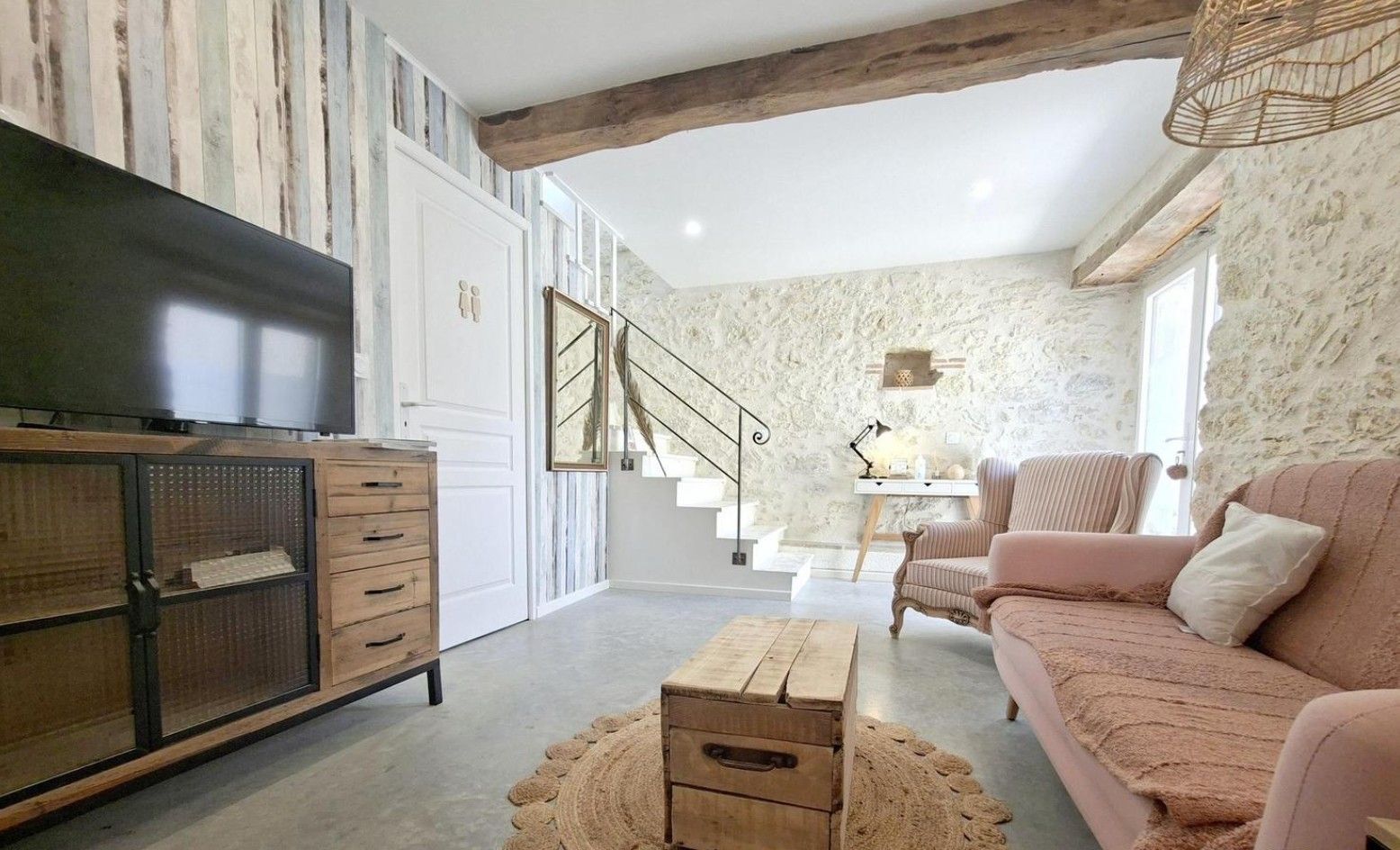 Un salon comprenant un canapé, une table basse, un téléviseur et un escalier menant à l’étage supérieur.