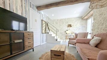 Un salon comprenant un canapé, une table basse, un téléviseur et un escalier menant à l’étage supérieur.