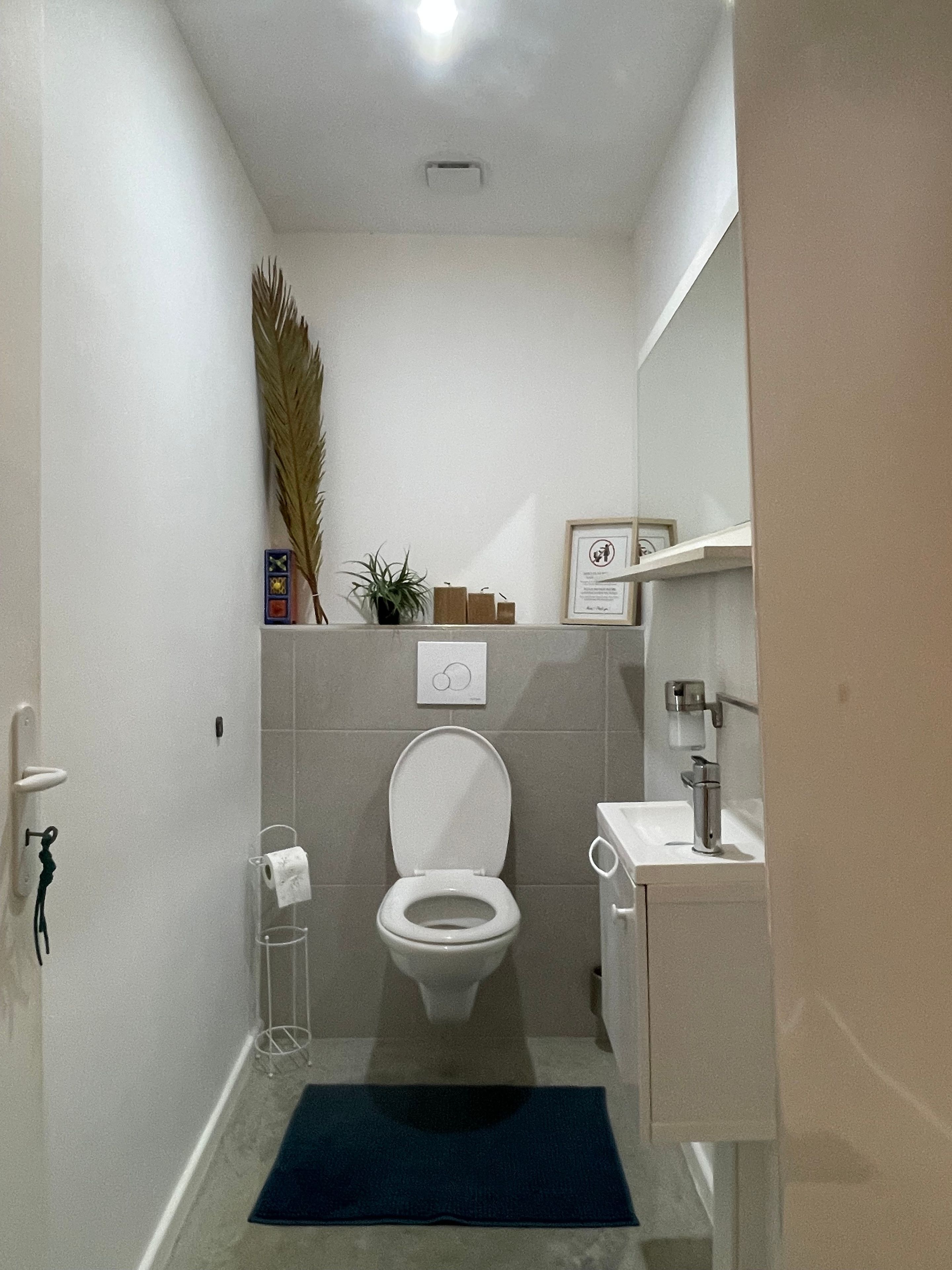 Un baño pequeño y moderno con inodoro, lavamanos y espejo.