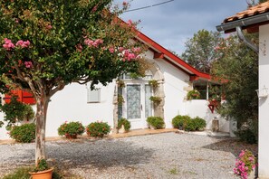 Un bâtiment blanc avec un toit rouge, entouré de gravier et de plantes en pot.