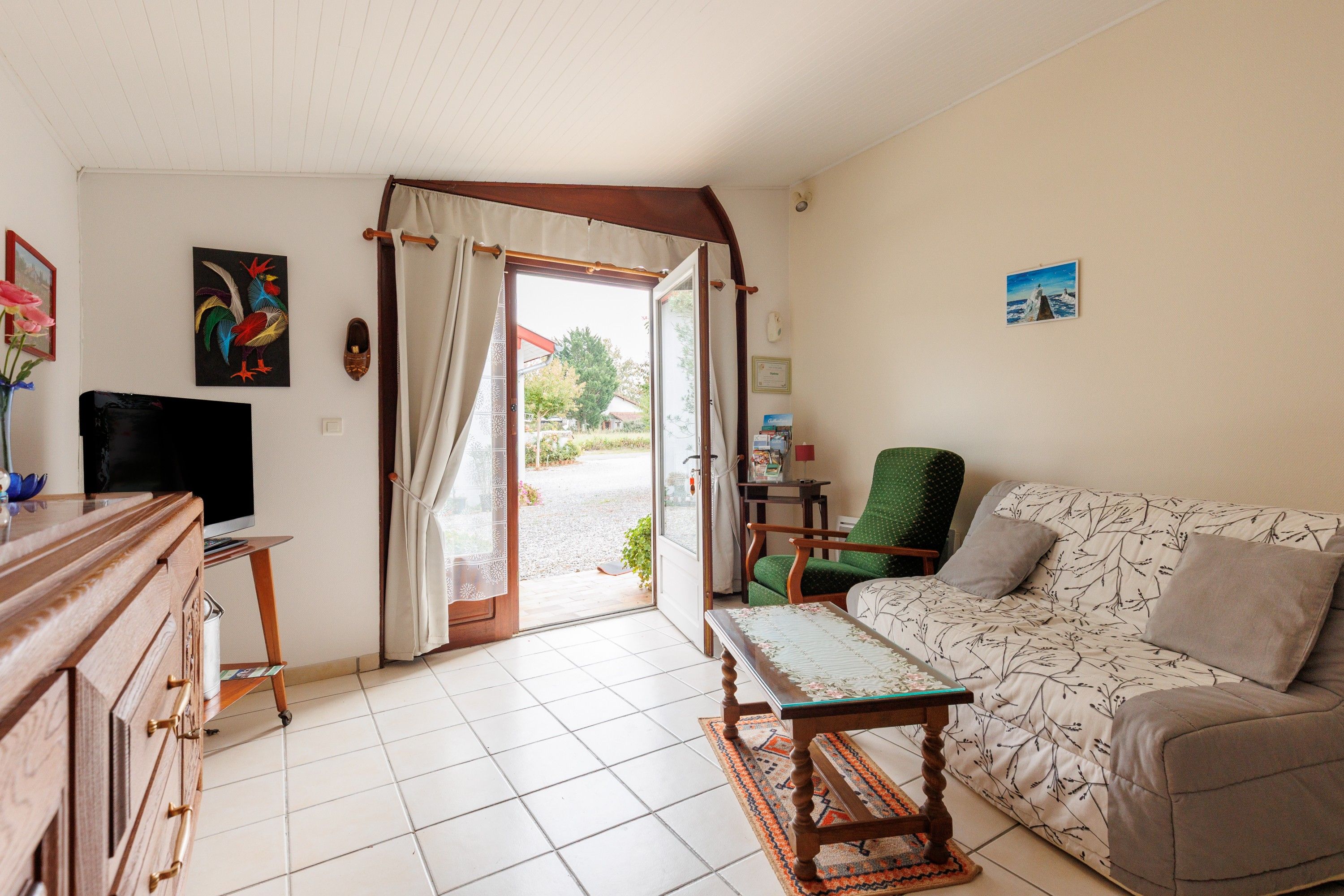 A room with a television, a sofa, a chair, a table, and a door leading outside.