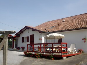 Ein weißes Gebäude mit rotem Dach und einer überdachten Außenveranda mit Stühlen und Tisch.