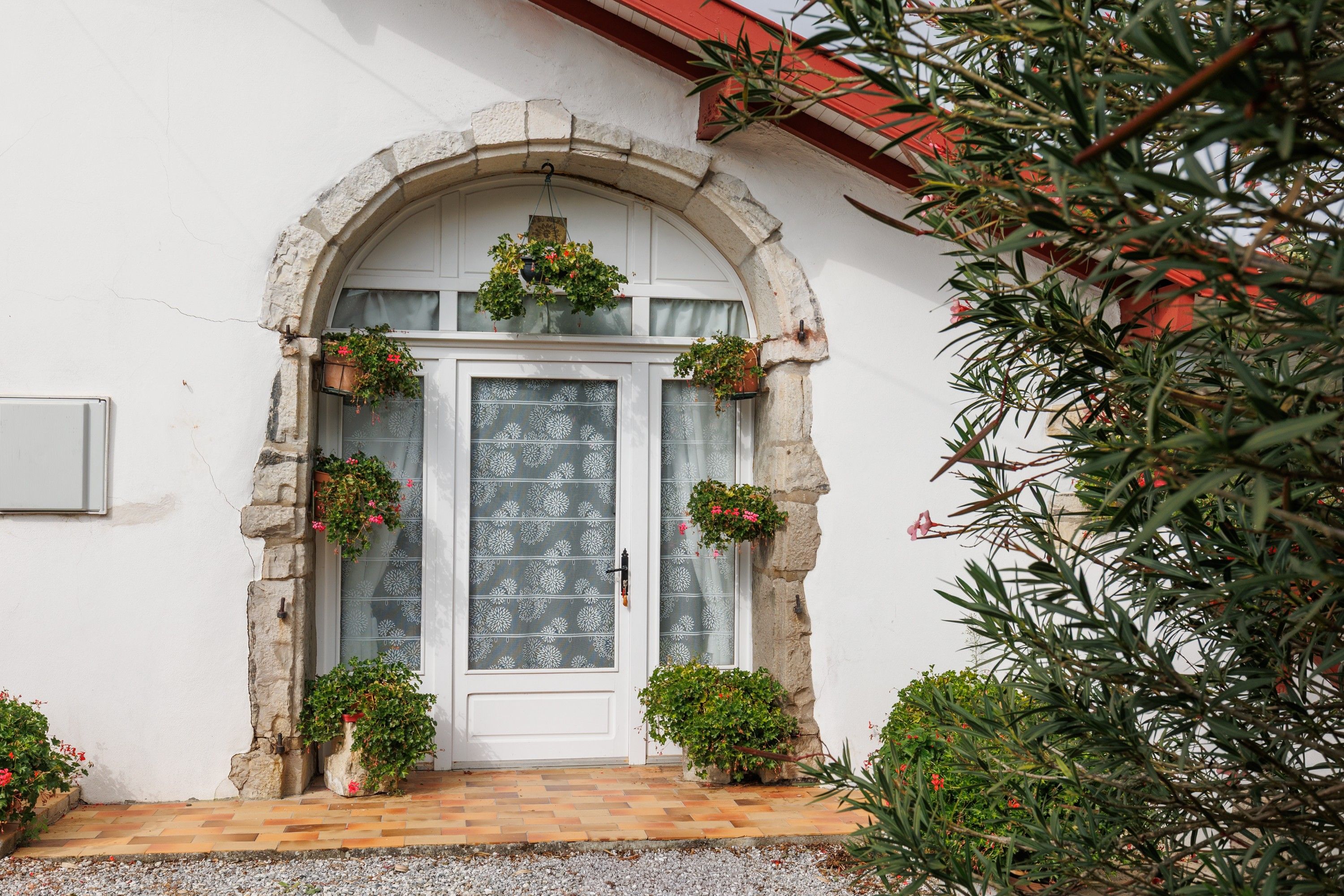 A building with a white facade, a stone archway entrance, and a tiled entrance area.
