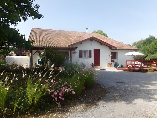 Ein zweigeschossiges Haus mit rotem Ziegeldach, weißer Fassade und einer roten Tür.