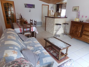 A living room with a sofa, a dining table with chairs, a kitchen area, and a bar stool. - Gîte Chez Françoise et Jean: Natural Air Conditioning in Saint-Lon-les-Mines (Saint-Lon-les-Mines)