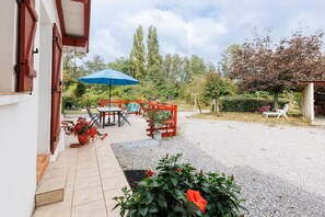 A patio with a table and chairs, a blue umbrella, and potted plants. - Gîte Chez Françoise et Jean: natural air conditioning in Saint-Lon-les-Mines (Saint-Lon-les-Mines)