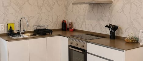 A modern kitchen with a marble backsplash, stainless steel appliances, and a wooden floor.