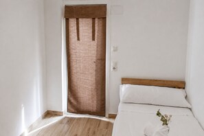 A bedroom with a wooden bed frame, white bedding, and a wooden floor. - Casa El Calvario, where you can take a break, relax, and enjoy time with family and friends. (Bolbaite)