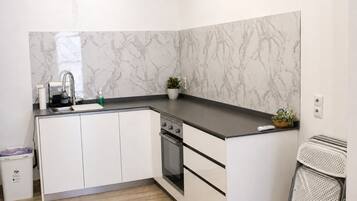 A modern kitchen with white cabinets, a marble backsplash, and a built-in oven.
