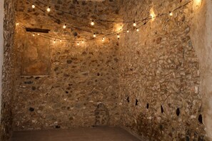 A stone-walled room with string lights, a bed, and a small window. - Casa El Calvario, where you can take a break, relax, and enjoy time with family and friends. (Bolbaite)