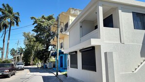 Ein modernes, zweistöckiges Gebäude mit weißer Fassade, einer blauen Tür und einer sichtbaren Treppe.