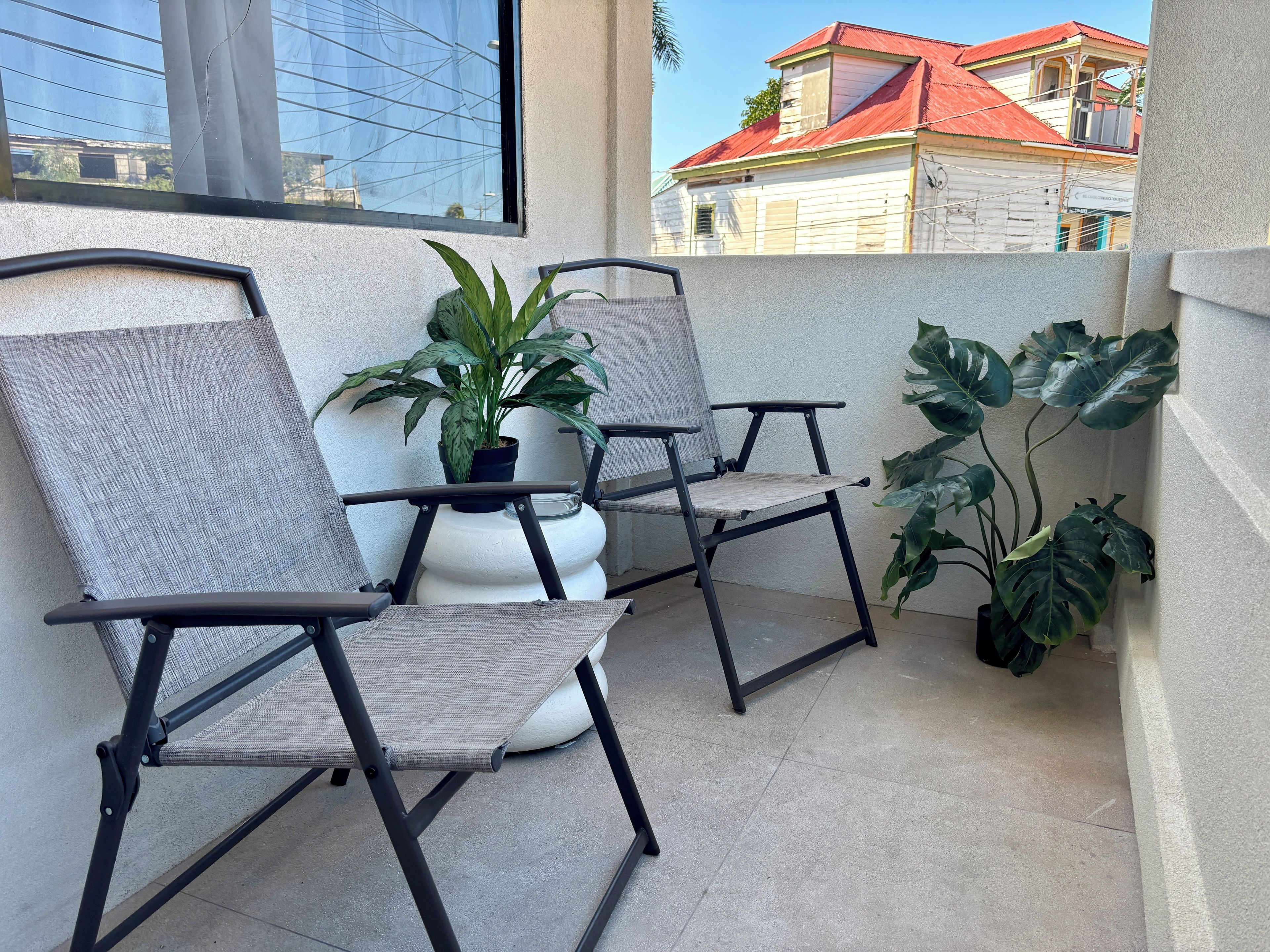 A balcony with two chairs and potted plants.