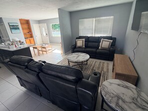 Ein modernes Wohnzimmer mit einem schwarzen Ledersofa, einem Marmortisch und einem Holznachttisch.