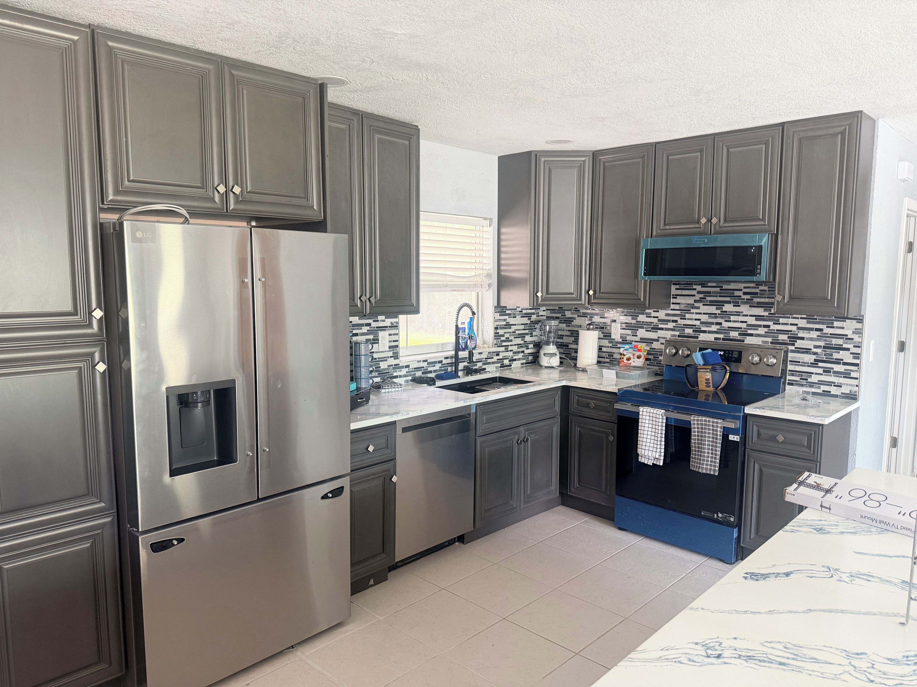 Una cocina moderna con electrodomésticos de acero inoxidable, armarios oscuros y salpicadero de azulejos.