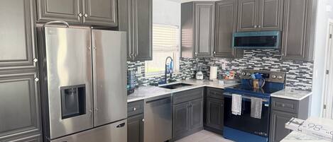 Una cocina moderna con electrodomésticos de acero inoxidable, armarios oscuros y salpicadero de azulejos.