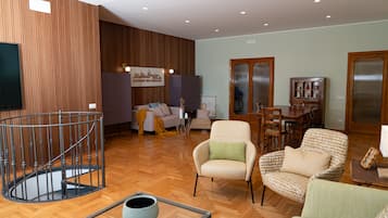Amplia sala de estar con piso de madera, un conjunto de sofás, una mesa de comedor y una escalera.