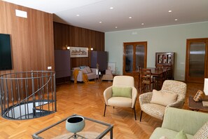Uma sala de estar ampla com piso de madeira, um conjunto de sofás, uma mesa de jantar e uma escada.