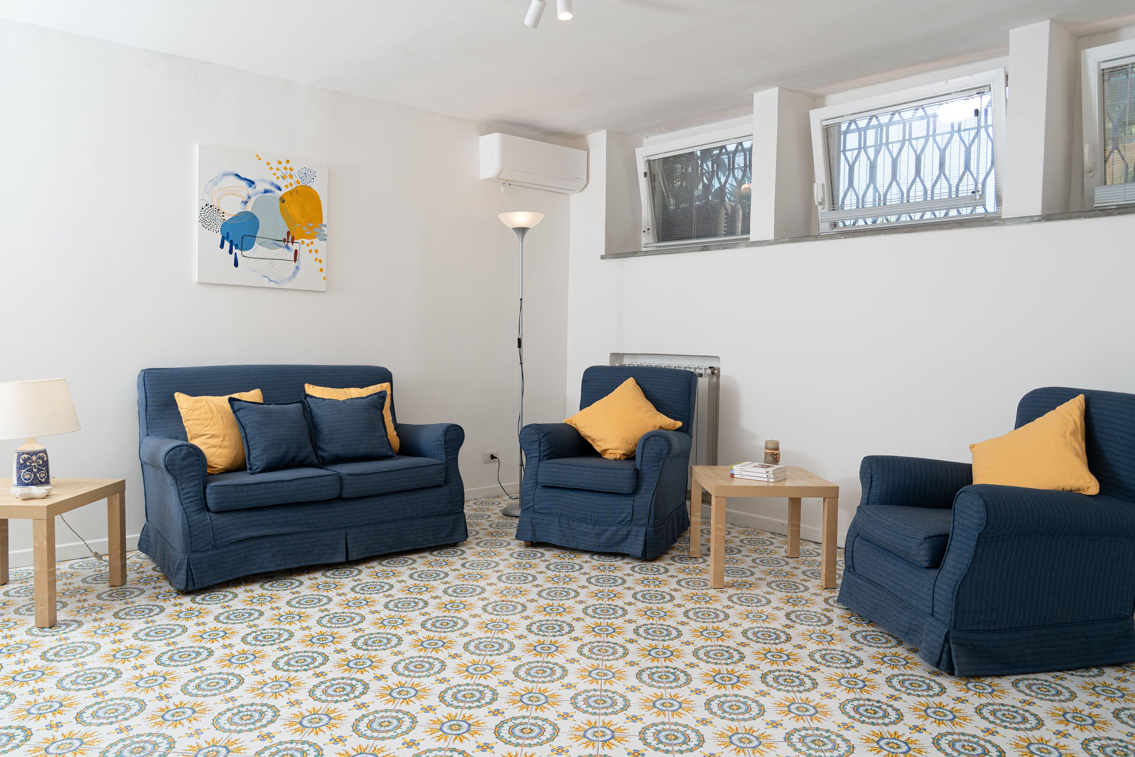 A living room with two blue sofas, a floor lamp, and a patterned floor.