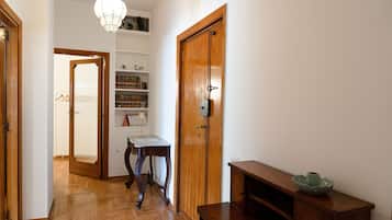 Un couloir avec un plancher en bois, une porte en bois, un bureau et une bibliothèque.