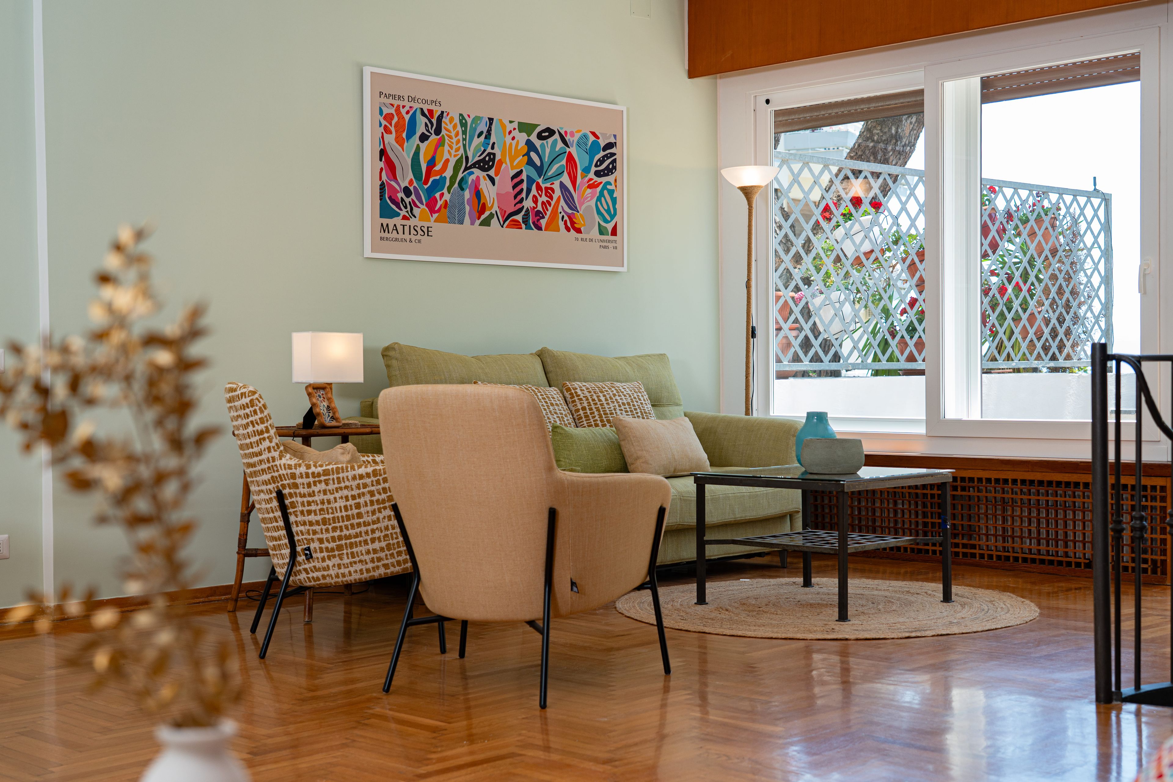 Uma sala de estar com sofá, poltronas, mesa de centro e um quadro na parede.
