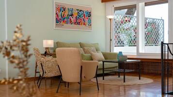 Uma sala de estar com sofá, poltronas, mesa de centro e um quadro na parede.