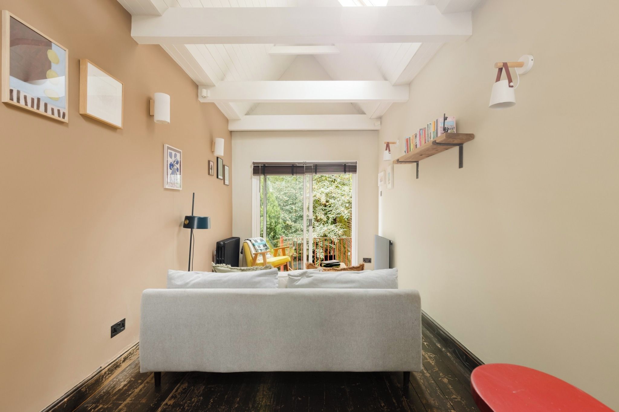 Une chambre moderne avec un grand lit, une fenêtre donnant sur un paysage verdoyant et une bibliothèque remplie de livres.