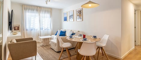 A modern dining area with a round table, white chairs, and a hanging light fixture.