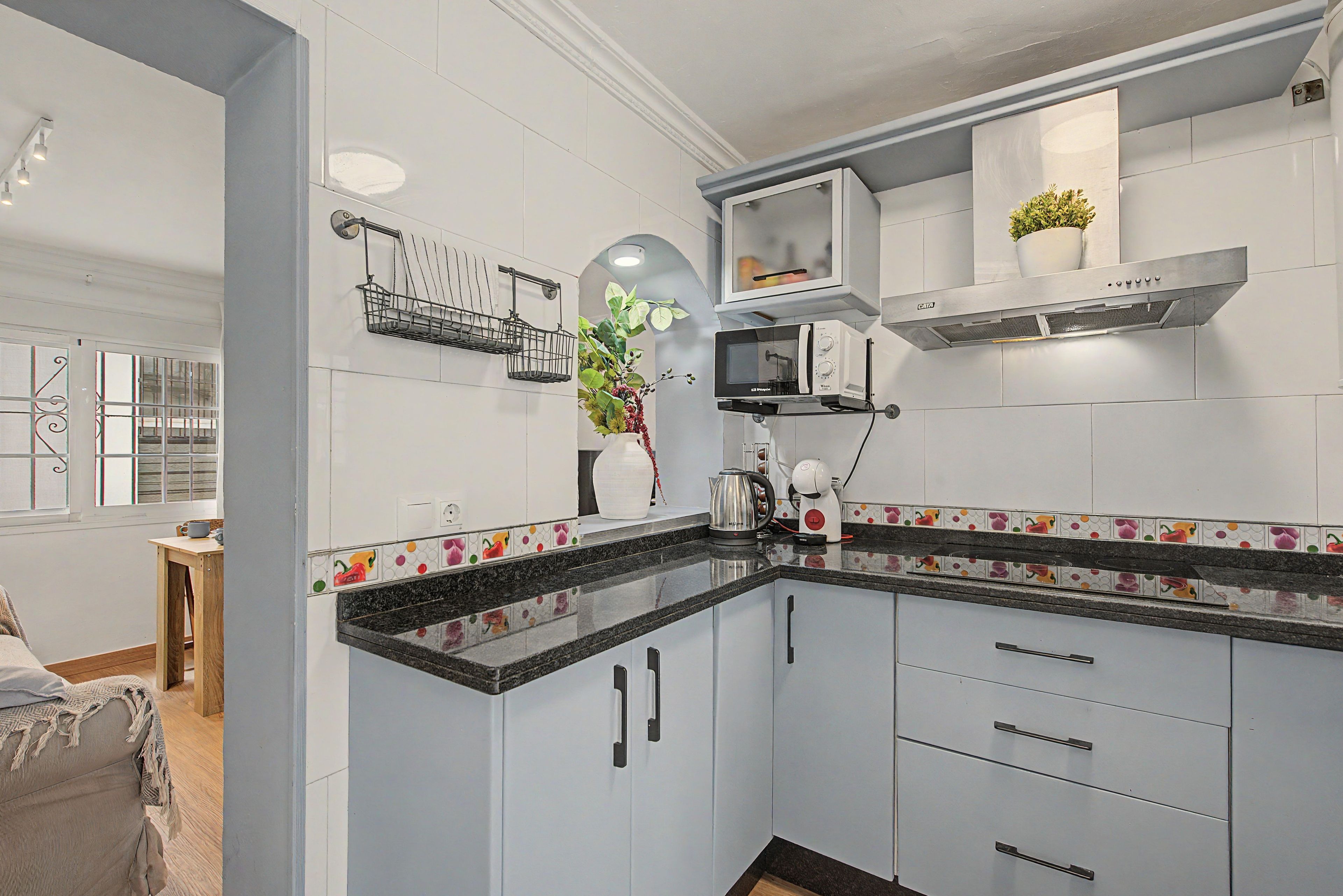 Una cocina moderna con armarios blancos, encimera negra y un microondas.