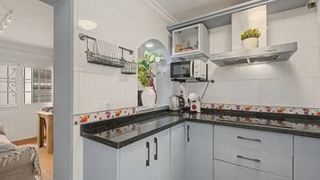 Una cocina moderna con armarios blancos, encimera negra y un microondas.