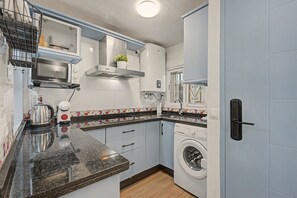 A compact kitchen with a built-in oven, a microwave, a kettle, and a washing machine.